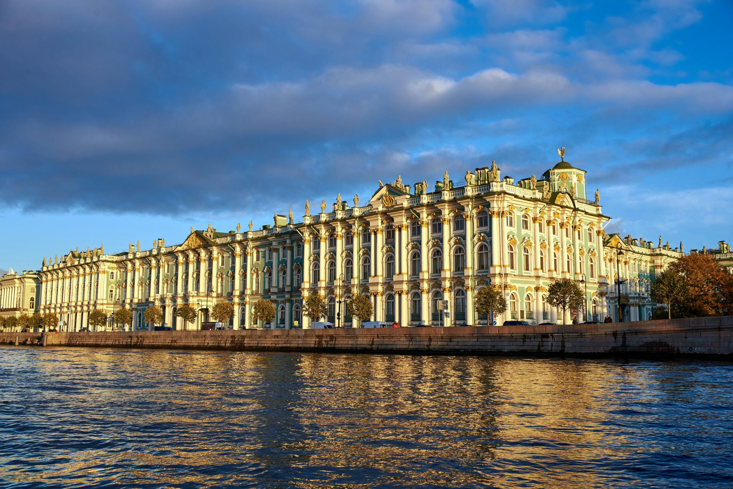 Aerial view of Saint Petersburg skyline at dusk, with prominent landmarks like the Hermitage Museum and Neva River highlighted.